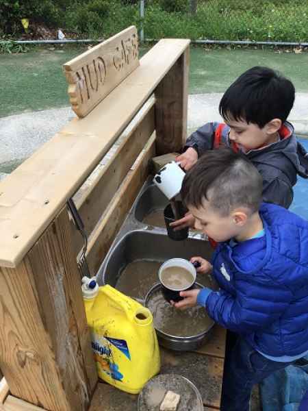 boys playing in an outdoor mud kitchen